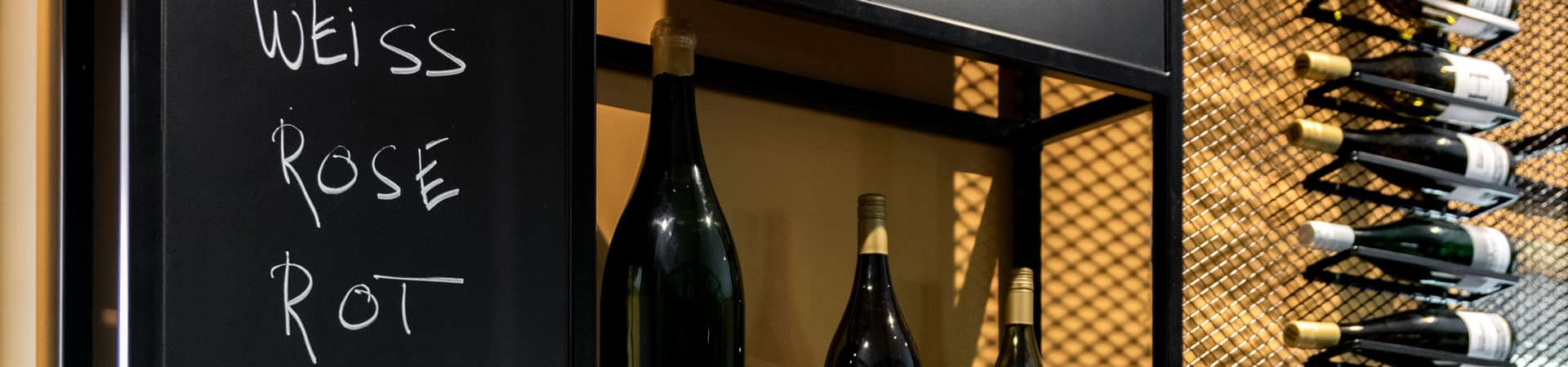 Verschiedene Weinflaschen des Weinguts Heinrichshof in einem Regal präsentiert Verschiedene Weinflaschen des Weinguts Heinrichshof in einem Regal präsentiert