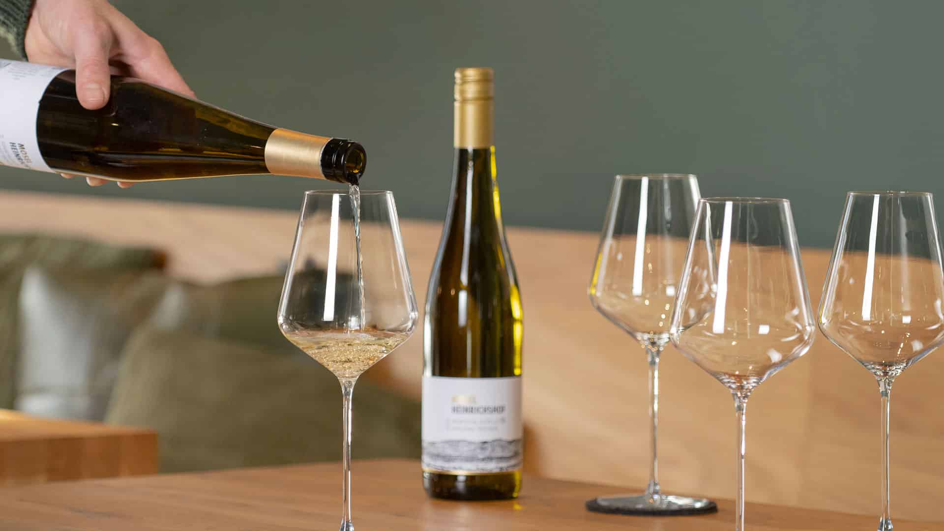 Hand schenkt Wein aus einer Flasche in ein Glas in der Vinothek Weinprobe